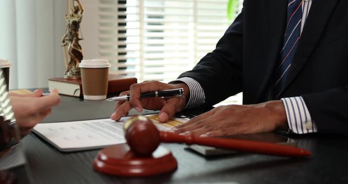 Lawyer explaining contract agreement to client in office while reviewing legal documents, representing legal consultation, justice process, and professional legal services.