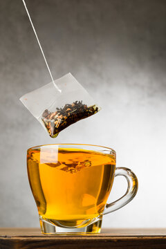 Glass cup of tea on wooden table with tea filter.