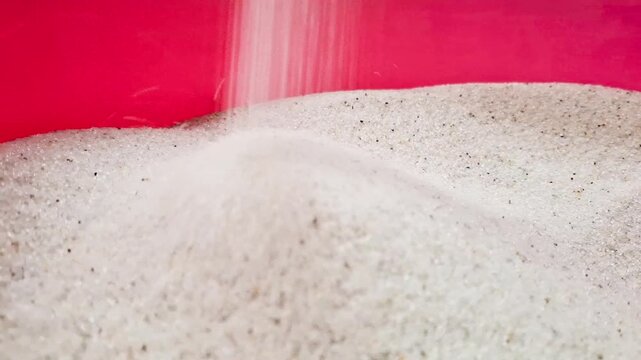 White sand flowing from mill machine during work to bucket.