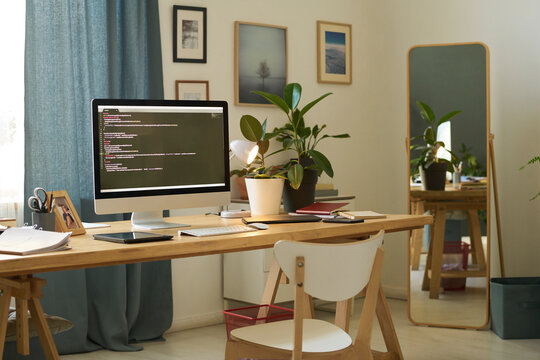 Home office with computer displaying programming code on a working table