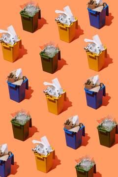 Colorful waste bins with sorted recycling on orange background