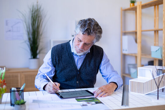 Confident architect working on tablet with real estate project indoors