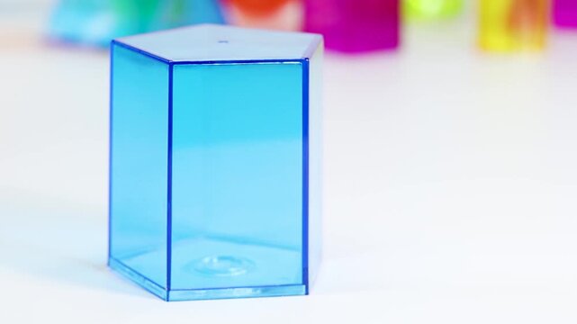Hand Placing a Blue Hexagonal Prism on a White Surface