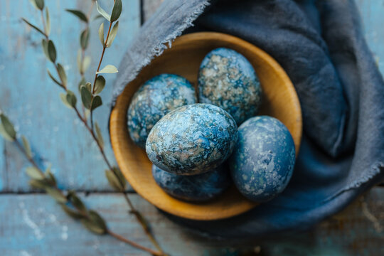 Blue Easter eggs dyed naturally with hibiscus in wooden bowl