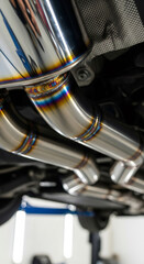 Obraz premium Close up of shiny metal exhaust pipe with colorful weld seams, part of car undercarriage repair and service in garage.