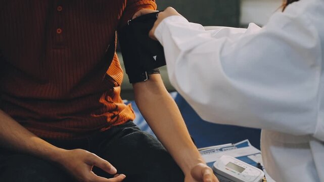 Female doctor measuring blood pressure of male patient in hospital