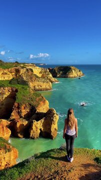 Woman tourist contemplating beautiful rocky cliff and Atlantic Ocean, Algarve in Portugal