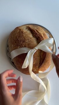 Artisan Sourdough Bread Loaf Decorated with a Ribbon on a Rustic Table