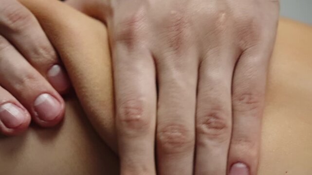 Close-up of therapist hands performing deep tissue massage and myofascial release on a client shoulder, applying kneading pressure for pain relief in physical therapy.