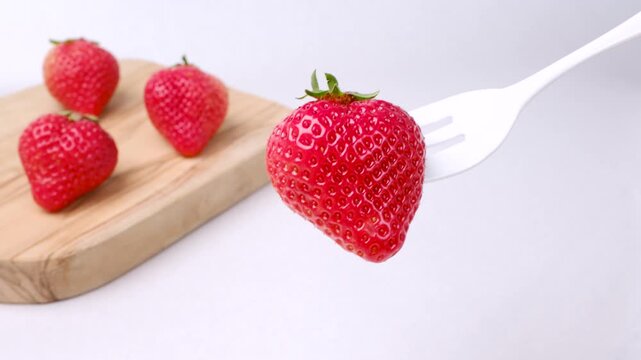 木のボードの前でフォークであげたあまおう苺
