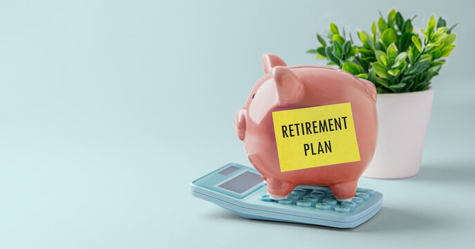 Retirement savings plan concept, Piggy bank on calculator with Retirement plan sticky note, small plant on blue background