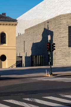 Daylight urban street intersection with crosswalk and traffic light casting shadow near modern architecture emphasizing safety and mobility flow
