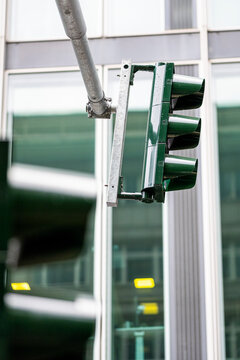 Closeup traffic light signal at urban intersection with pole and glass background in daytime creating blur and motion for safety concepts