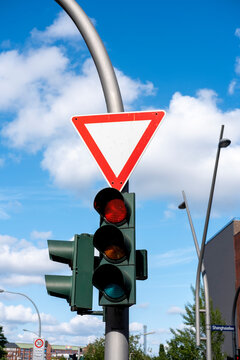 Traffic light signal below yield sign at street intersection under blue sky showing urban safety and clear daytime visibility for navigation