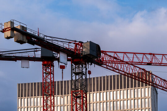 Overcast urban construction crane with building rooftop steel structure showing skyline development progress in germany with industrial worksite detail
