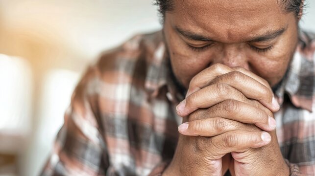 Man praying with hands clasped together. Devoted person showing faith and spiritual connection. Religious concept of hope, belief, humility and meditation. Human emotion and peace.
