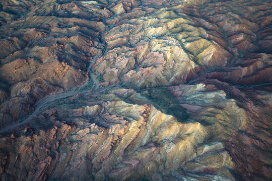 Aerial view of a landscape with deep canyons and hillsides, where shadows highlight the textures of the earth, Indio, California, United States.