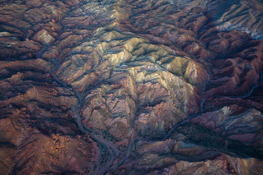 Aerial view of sun-kissed mountains casting long shadows across the rugged terrain, revealing a tapestry of textures and tones, Indio, California, United States.