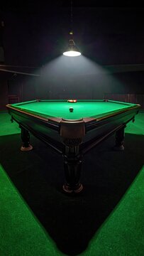 Moody dimly lit pool hall interior featuring a green felt billiard table under a hanging spotlight creating dramatic shadows and a focused atmosphere