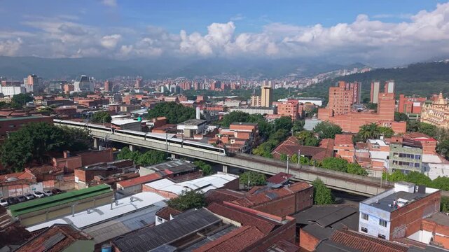Tram in Medell&iacute;n with city skyline, known for Comuna 13 and Metrocable