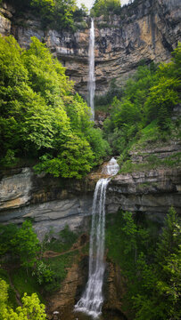 Aerial view of the Cascade de la Queue du Cheval waterfall cascading down a cliff face amidst a lush green forest, Saint-Claude, Bourgogne-Franche-Comte, France.