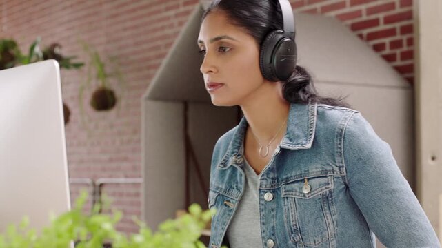 Headphones, businesswoman and eating noodles with computer, streaming audio or review for news story. Chinese food, hungry and person in startup office for music, reading report and creative article
