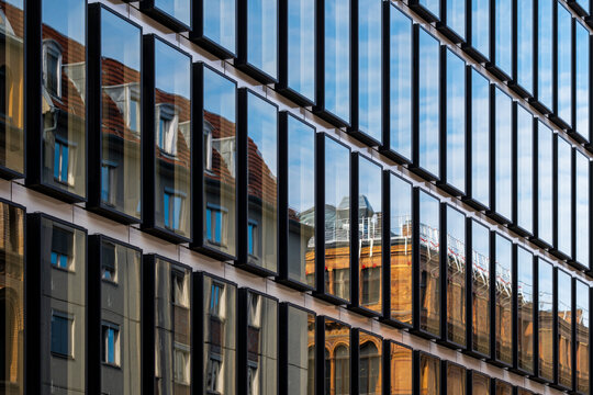 Reflective urban glass facade with linear rhythm creating modern corporate architecture pattern for business real estate concepts and abstract background design