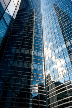 Upward view of a modern glass tower skyscraper with reflective architecture and strong perspective creating a vertical corporate city background for business growth themes