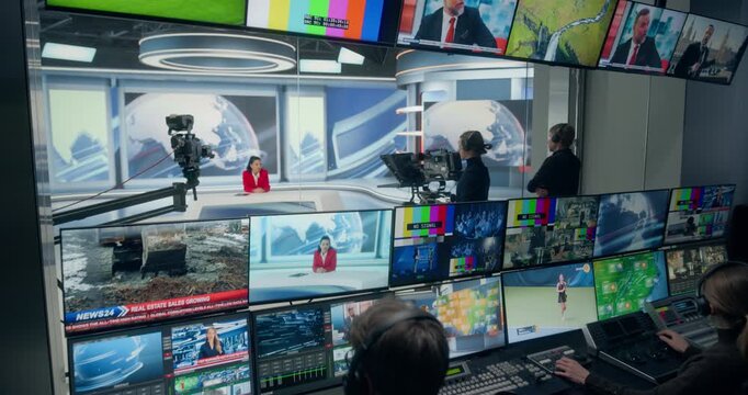 Backstage TV Station Production Control Room Manages a Live News Broadcast as Operators Monitor Screens, Switch Camera Feeds, Film Anchor in Studio. Zoom Out Shot Cable Channel Network 