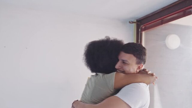 In a cozy apartment, a heartfelt embrace between a woman with vibrant, natural hair and a man highlights the warmth of their home renovation in their beautifully updated living space.