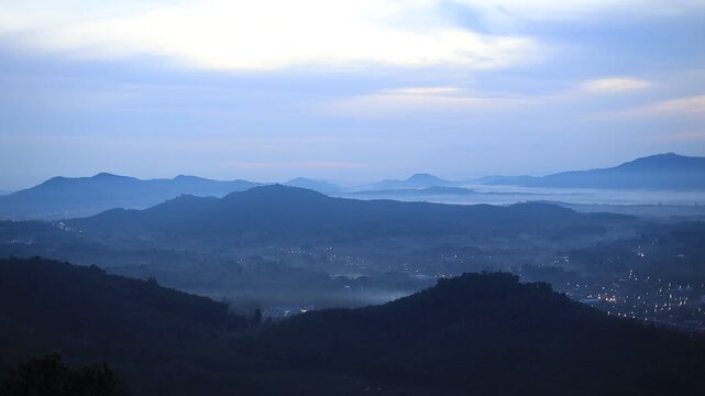 Natural video background of a high-angle atmosphere on a mountain that overlooks the surrounding scenery(mountains, trees,sea)from a scenic vantage point,with a wooden chair for sitting and resting