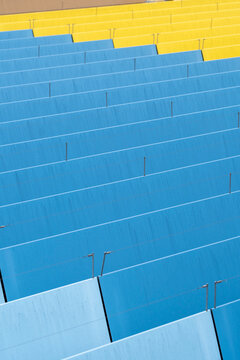 Stadium seats and steps in blue and yellow showing minimal geometry pattern texture as vibrant background for copy space design template