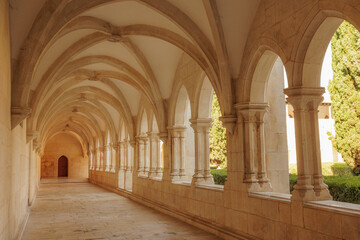 Obraz premium A long perspective view of a limestone Gothic corridor with vaulted ceilings and elegant stone arches in the European Monastery. Stock photo