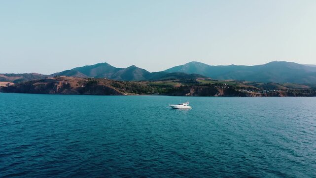 White Yacht Sailing on Calm Mediterranean Sea with Mountain Backdrop