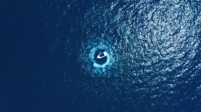Aerial View of Motorboat Completing Circle Maneuver on Glittering Blue Ocean