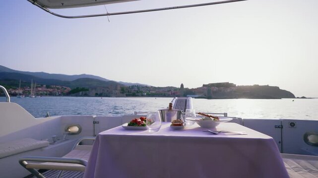 Luxury Yacht Deck Table with Food and Champagne Facing Coastal Village