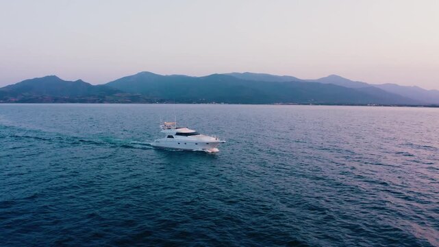 White Yacht with Golden Lights Sailing on Sea Against Mountain Range Dusk