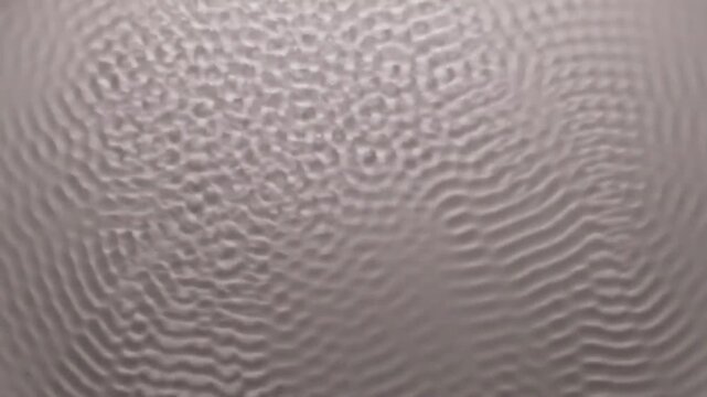 Abstract pattern of cymatics waves on a metallic surface, showing intricate geometric formations