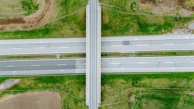 Aerial view of a concrete overpass cutting through a highway, flanked by fields of vibrant green grass, Sremska Mitrovica, Vojvodina, Serbia.