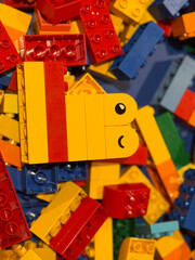 Fototapeta premium Cheerful yellow lego character on colorful bricks