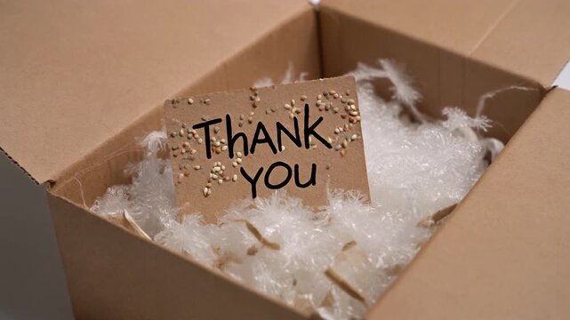 A heartfelt thank you note nestled within a cardboard box filled with soft white packing material