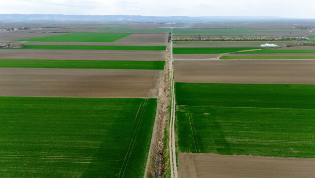 Aerial view of vibrant green and brown agricultural fields creating a patchwork quilt under a soft, overcast sky, Sremska Mitrovica, Vojvodina, Serbia.