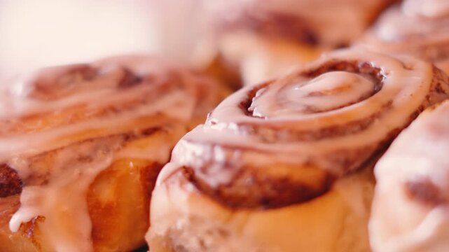 Freshly Baked Cinnamon Buns in Cafe Setting with Soft Natural Light. Sweet Bakery Treat with Icing Glaze.