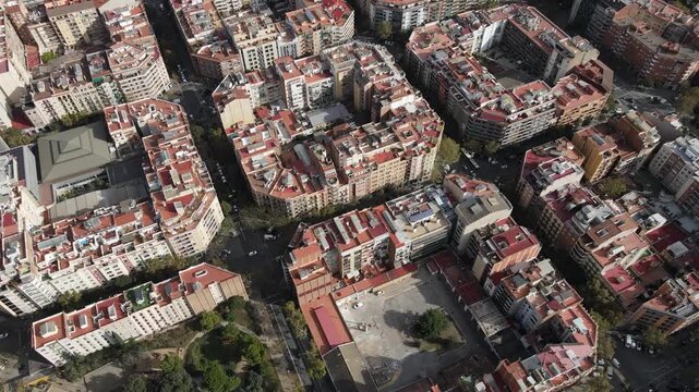 Drone flying away from Sagrada Familia showing park blocks and coast