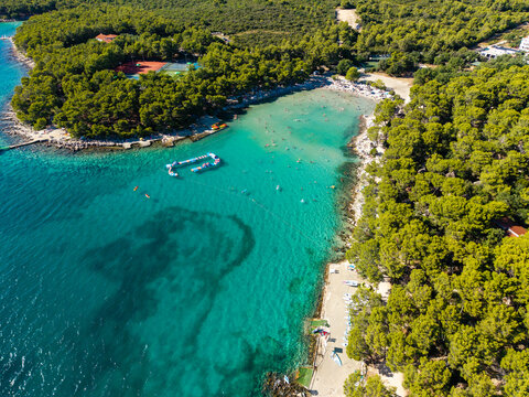 Aerial view of the cove with the turquoise water contrasting with the lush greenery and the sandy beach, Crvena Luka, Biograd na Moru, Zadarska zupanija, Croatia.