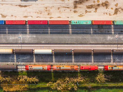 Aerial view of colorful cargo containers and trains, a symphony of industrial hues against the backdrop of lush greenery, Atessa, Abruzzo, Italy.
