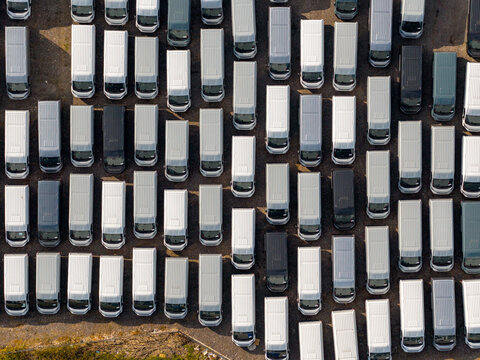 Aerial view of a grid-like array of neatly parked vans, their rooftops reflecting the sunlight in a pattern of whites and grays, Atessa, Abruzzo, Italy.