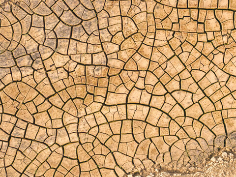 Aerial view of a parched earth, its cracked surface forming intricate patterns under the harsh sun, a mosaic of dryness and despair, Atessa, Abruzzo, Italy.
