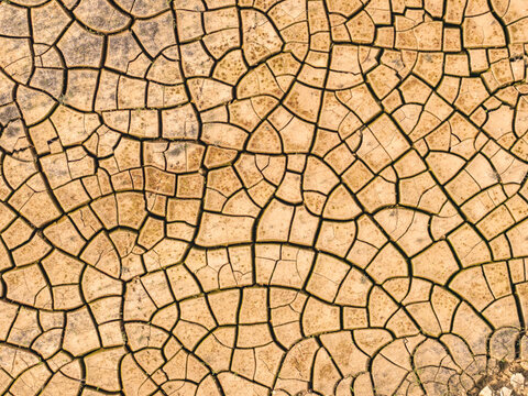 Aerial view of parched earth reveals a web of cracks, painted in earthy tones, speaking of aridity and resilience, Atessa, Abruzzo, Italy.