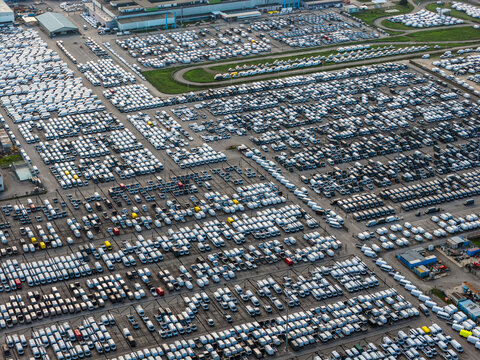 Aerial view of thousands of vehicles neatly arranged in rows, creating a textured landscape of whites, grays, and occasional pops of color, Atessa, Abruzzo, Italy.